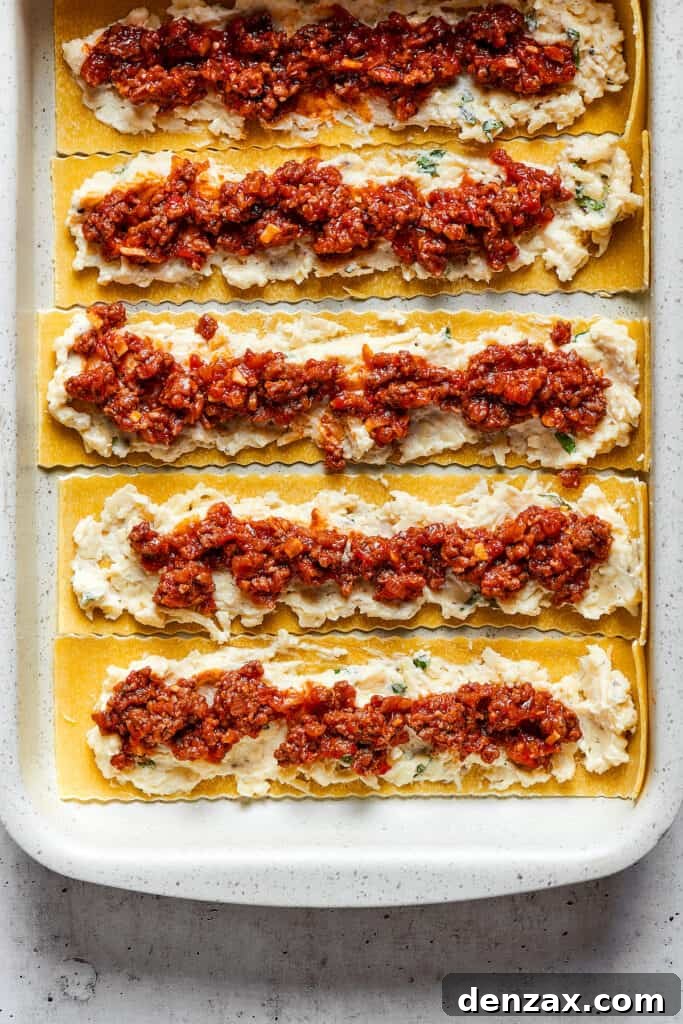 Overhead view of lasagna noodles covered with a cheese mixture and a ragu.