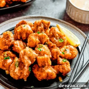 A plate of bang bang chicken with a lemon slice and a pair of chopsticks, next to a napkin and another lemon slice.