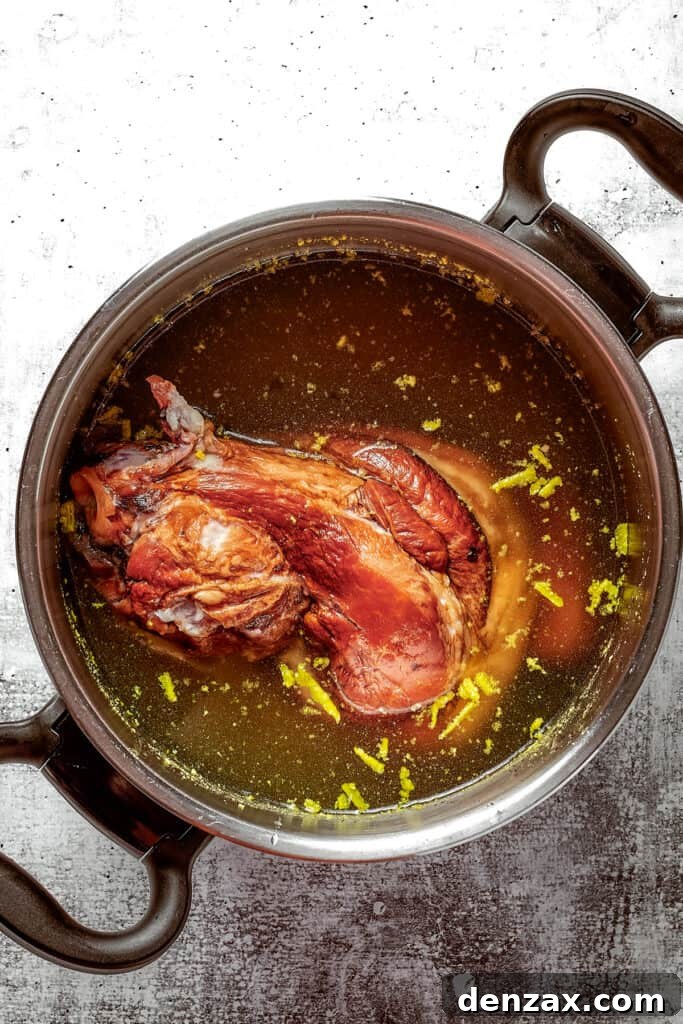 A stock pot filled with broth and a ham bone.