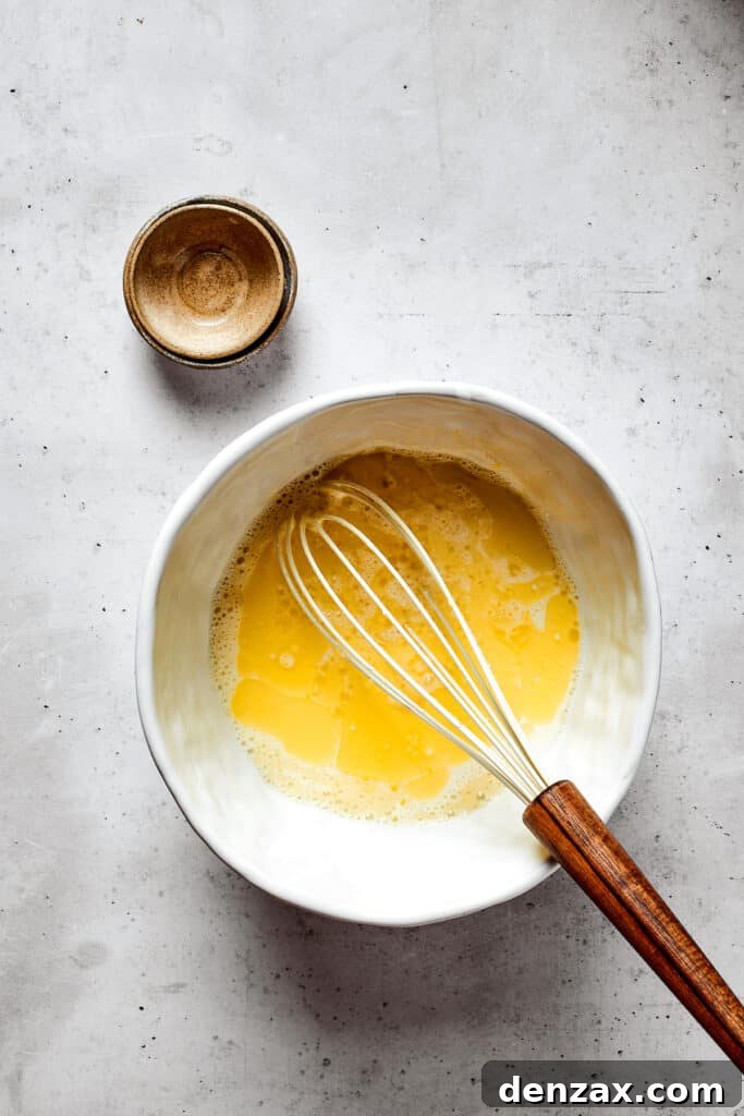Mixing wet ingredients in a bowl with a whisk.