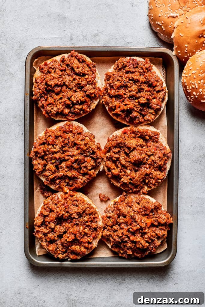 This easy Pizza Burger recipe is sure to become a family favorite! Meat filling is layered with pepperoni and melty mozzarella cheese. Six pizza burgers with meat are shown on a baking sheet.