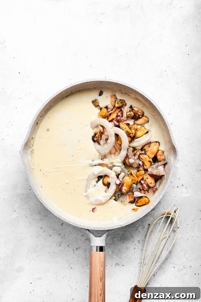 Folding seafood into the cheese sauce Adding seafood to the sauce.