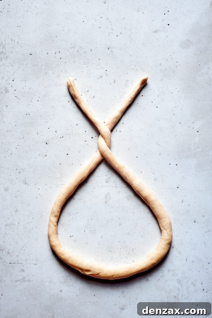 A rope of soft pretzel dough is formed into a pretzel.