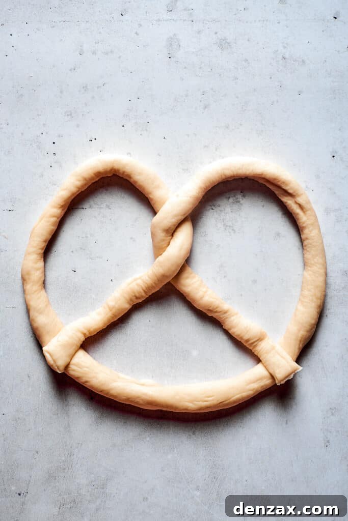 A rope of soft pretzel dough is formed into a pretzel.