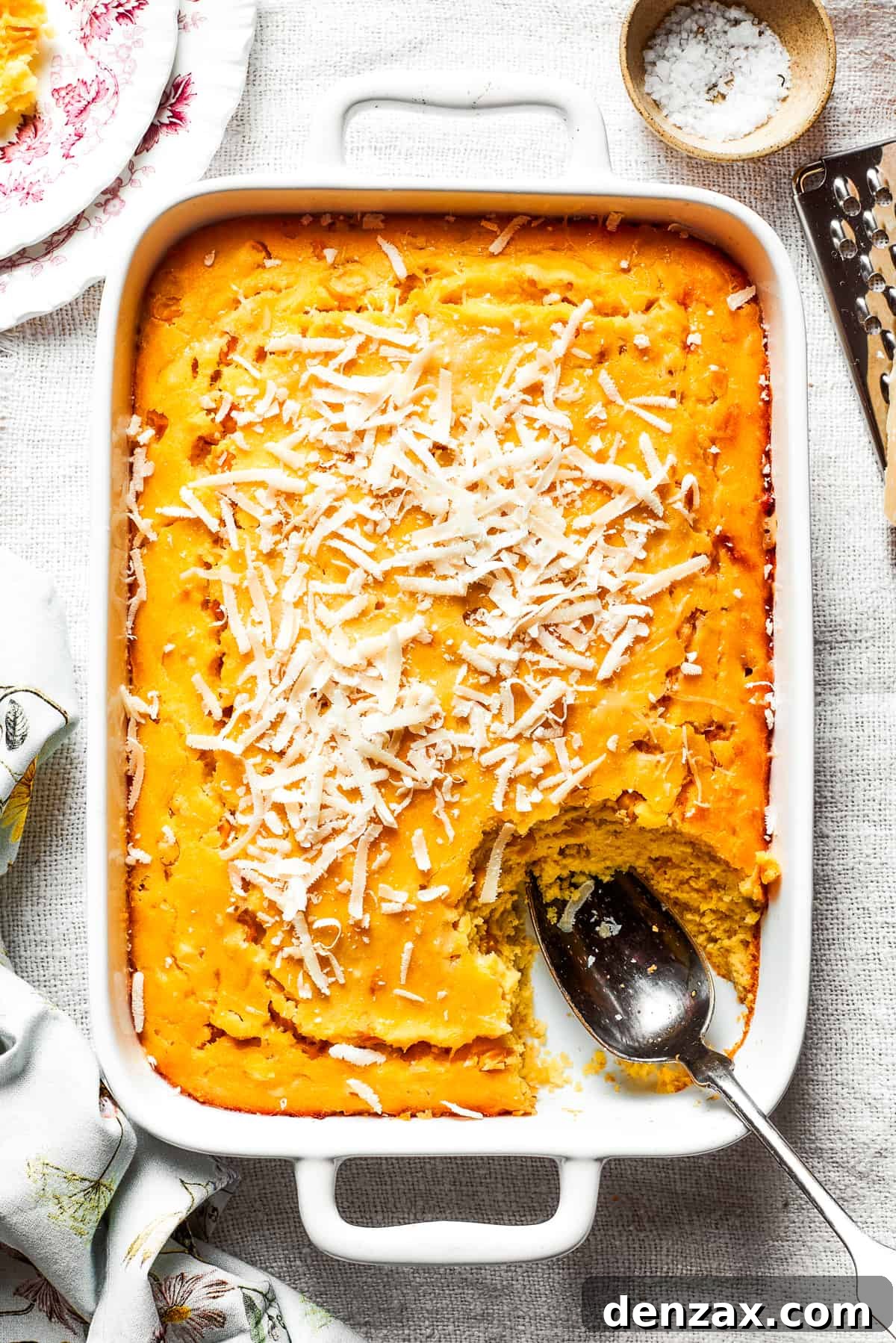 Corn Souffle is rich, creamy, and slightly sweet-savory. It's easily made with pantry and fridge staples, making it a great side dish. A white baking pan of baked corn souffle with a piece cut out and a spoon in the lower right side.