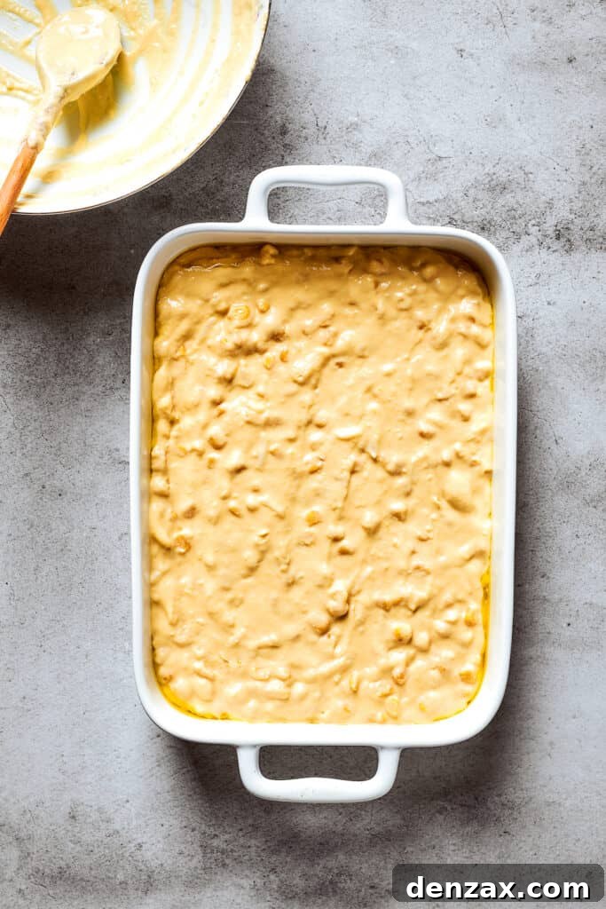 Corn Souffle is rich, creamy, and slightly sweet-savory. It's easily made with pantry and fridge staples, making it a great side dish. Corn souffle batter is shown in a white baking pan.