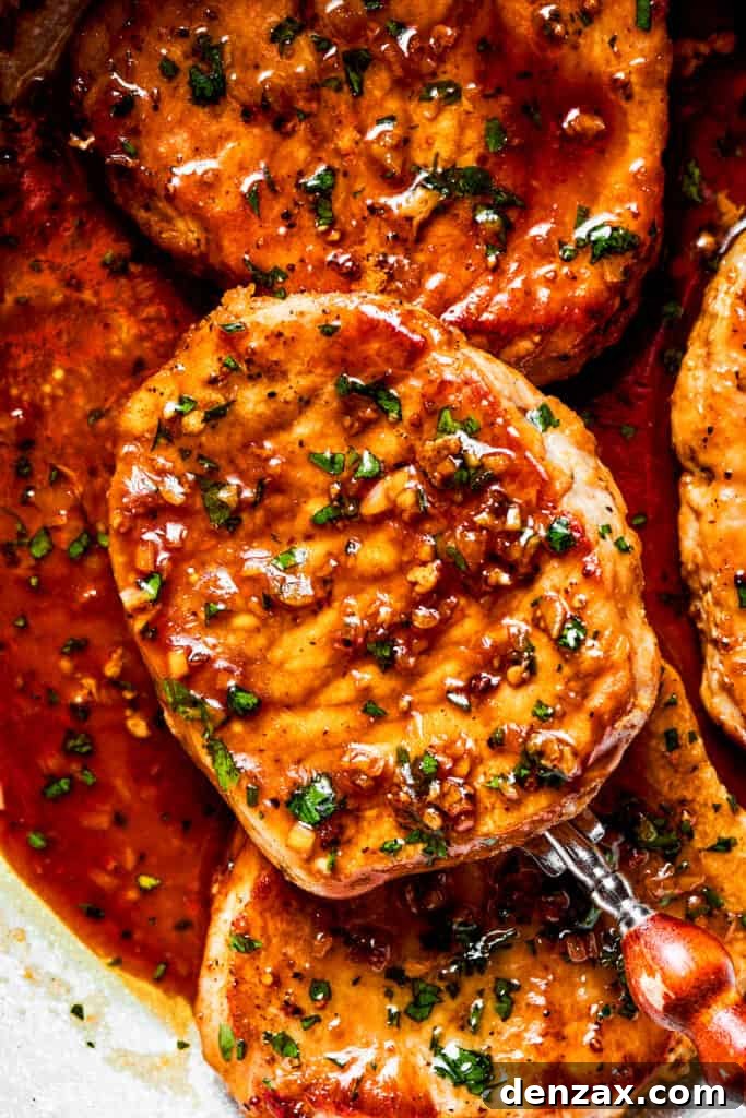 These Honey Garlic Pork Chops are the perfect blend of sweet-salty with a punch of extra flavor from minced garlic. Ready in 20 minutes! Close-up image of a spoon holding up a pork chop.