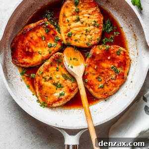 Easy Honey Garlic Pork Chops Recipe — Sweet & Savory Dinner Idea 2 Four honey garlic pork chops cooking in a skillet with a wooden spoon stirring through.