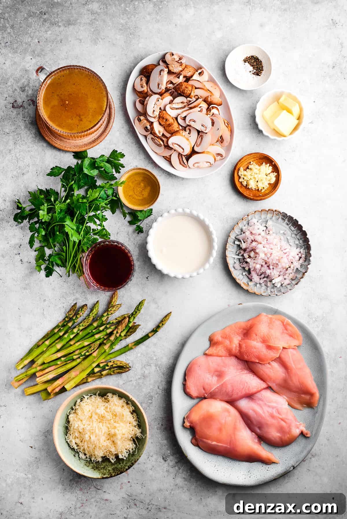 The ingredients for chicken madeira are shown portioned out: chicken, mushrooms, asparagus, parsley, salt and pepper, butter, olive oil, madeira, garlic, mozzarella, cream, broth.