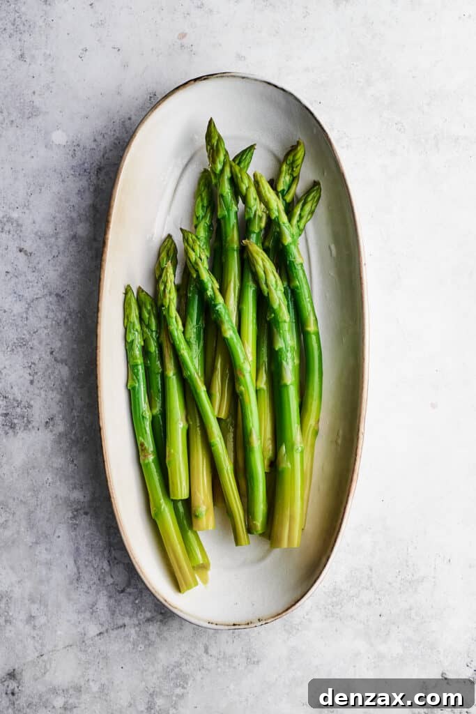 Asparagus for chicken madeira are arranged in an oval white baking dish.