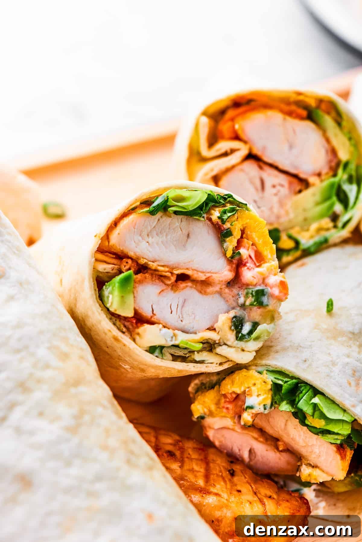 A halved buffalo chicken wrap shows the interior of chicken and vegetables.