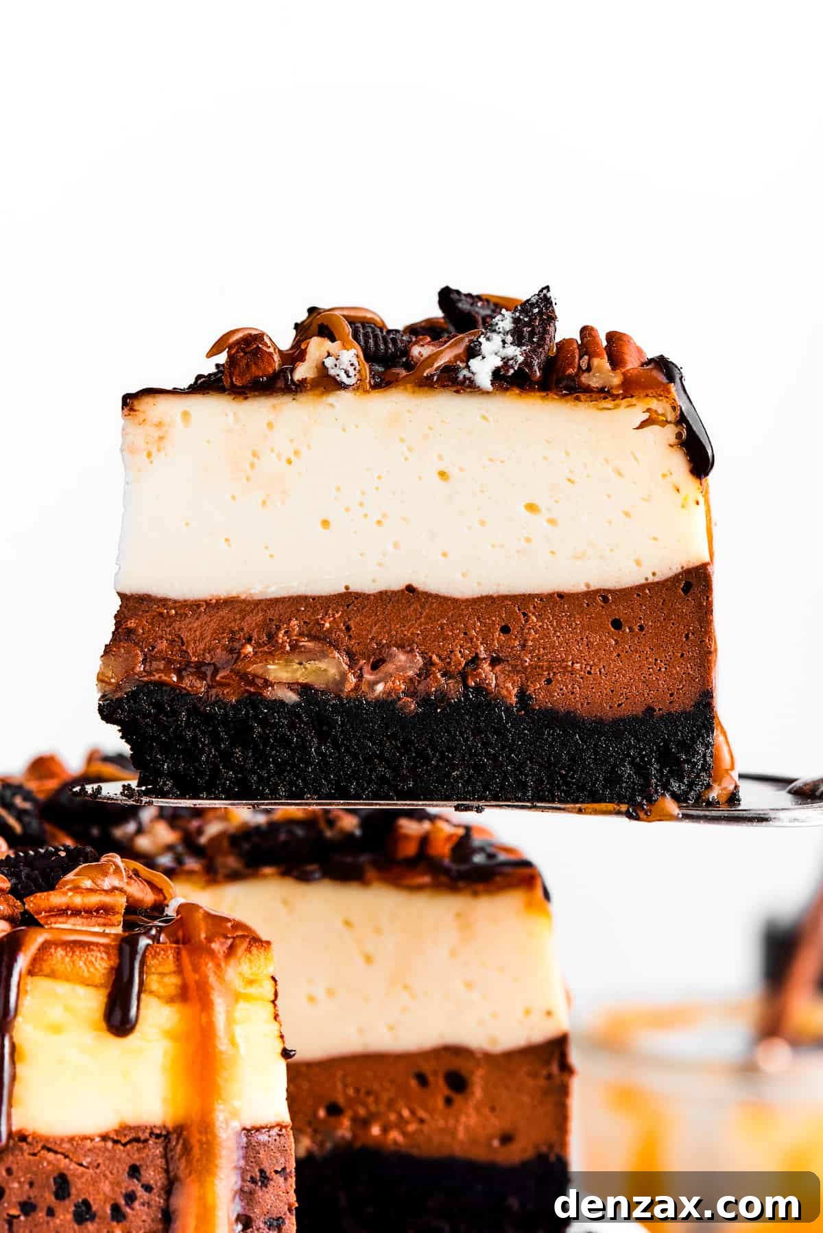 A cake server holding up a slice of turtle cheesecake.