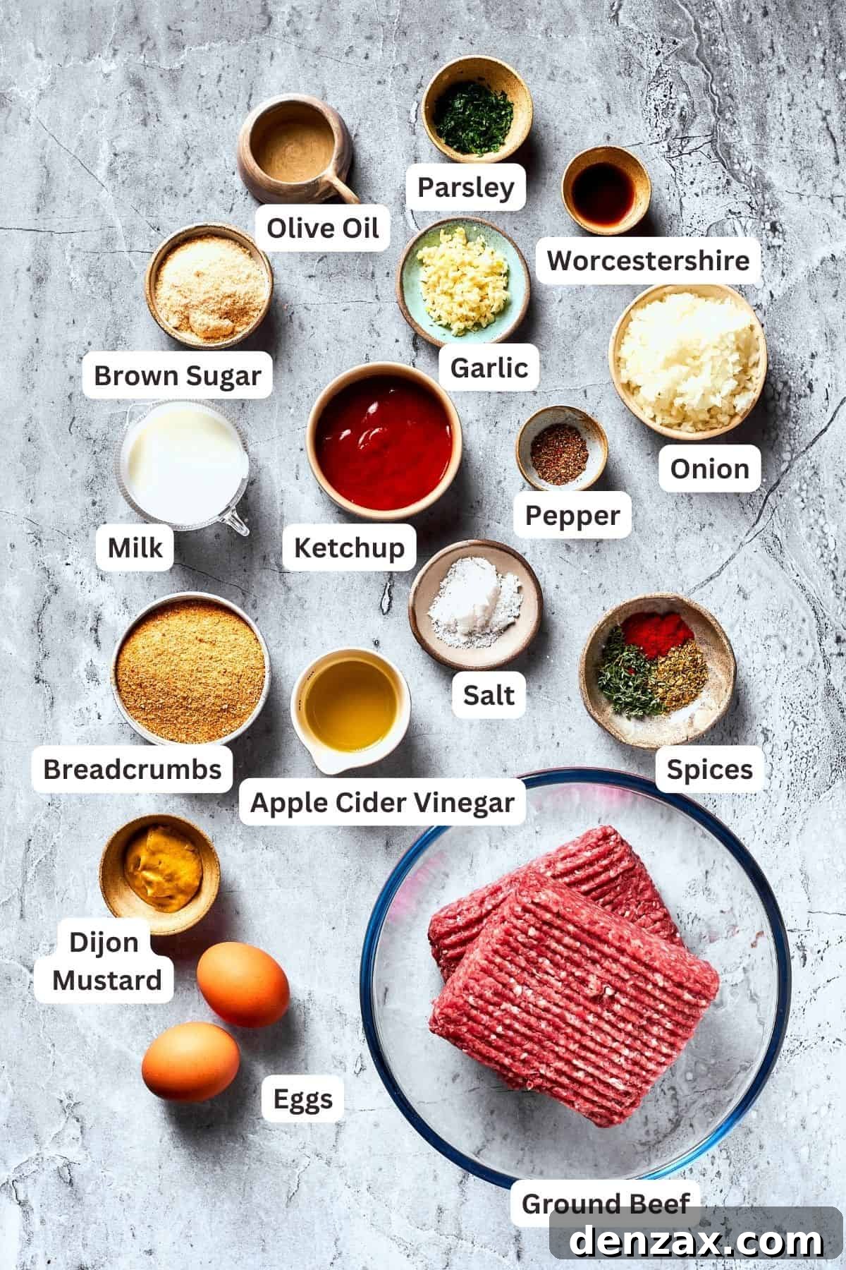 The ingredients for brown sugar meatloaf are shown portioned out: meat, ketchup, brown sugar, apple cider vinegar, salt and pepper, herbs, onion, garlic, breadcrumbs, Worcestershire sauce, eggs, olive oil.
