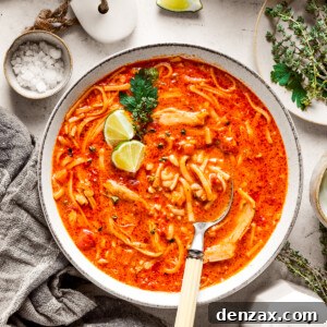 Two bowls of spicy chicken soup are shown with toppings arranged around them.