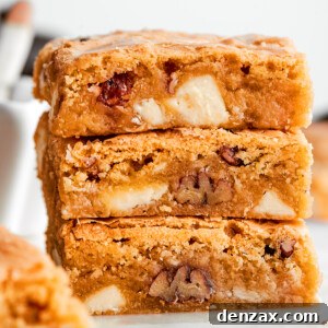 A stack of three blonde brownies with white chocolate chips and pecans visible.