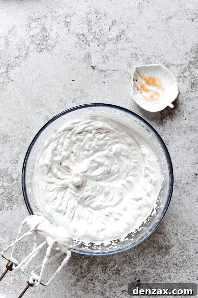 A bowl of freshly whipped cream with beaters above it.