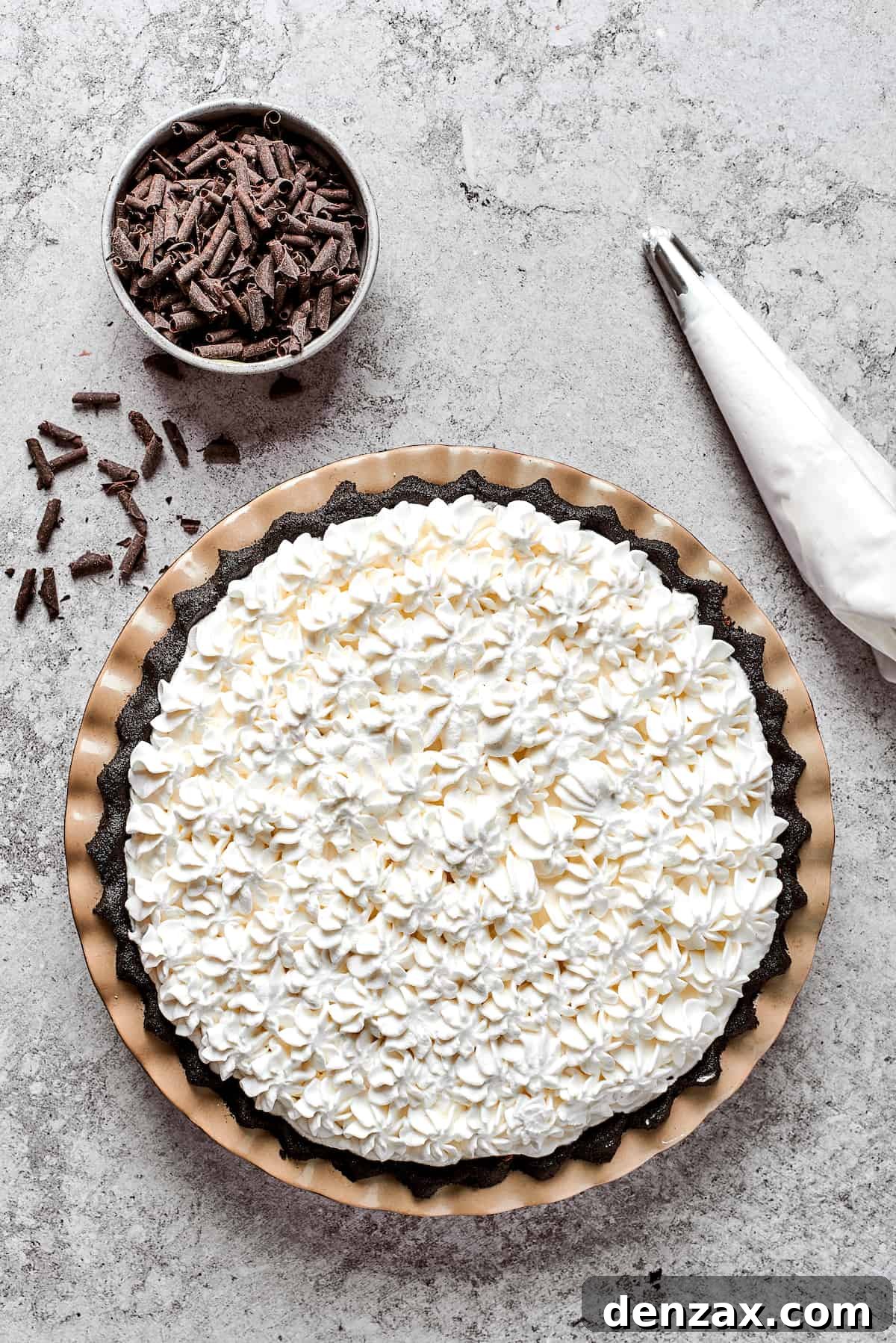 Whipped cream is piped on top of a French silk pie.