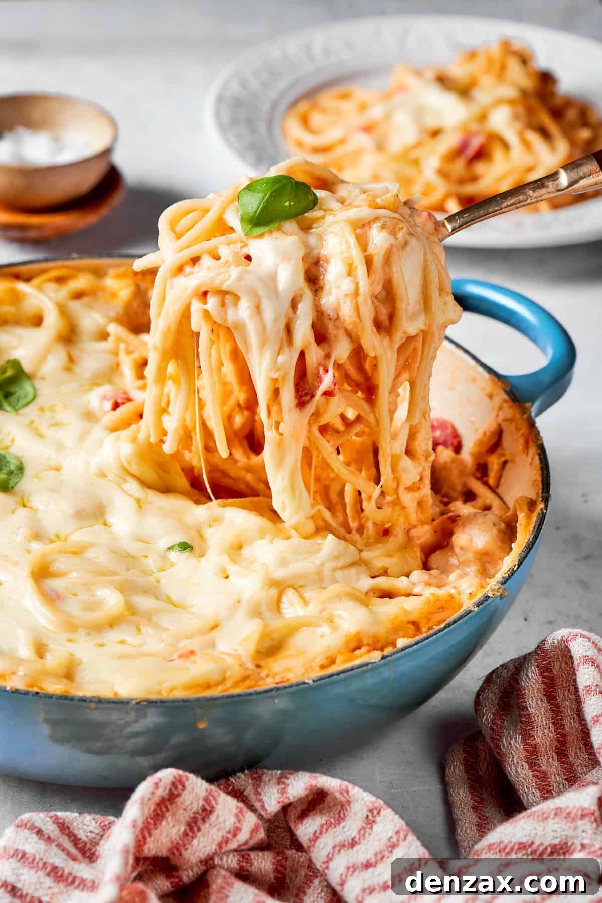 A serving utensil lifts out a portion of cheesy chicken spaghetti.