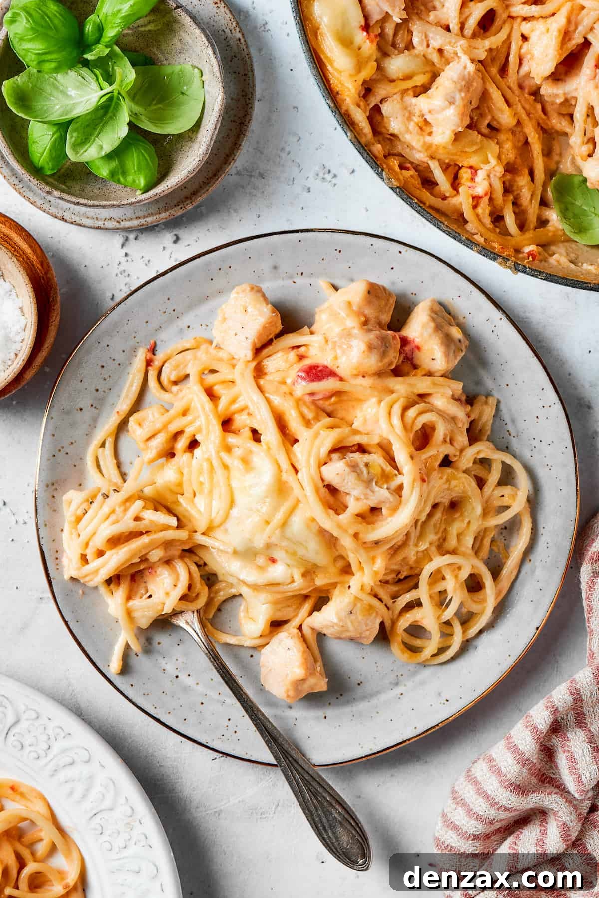 A plated serving of cheesy chicken spaghetti with a fork.