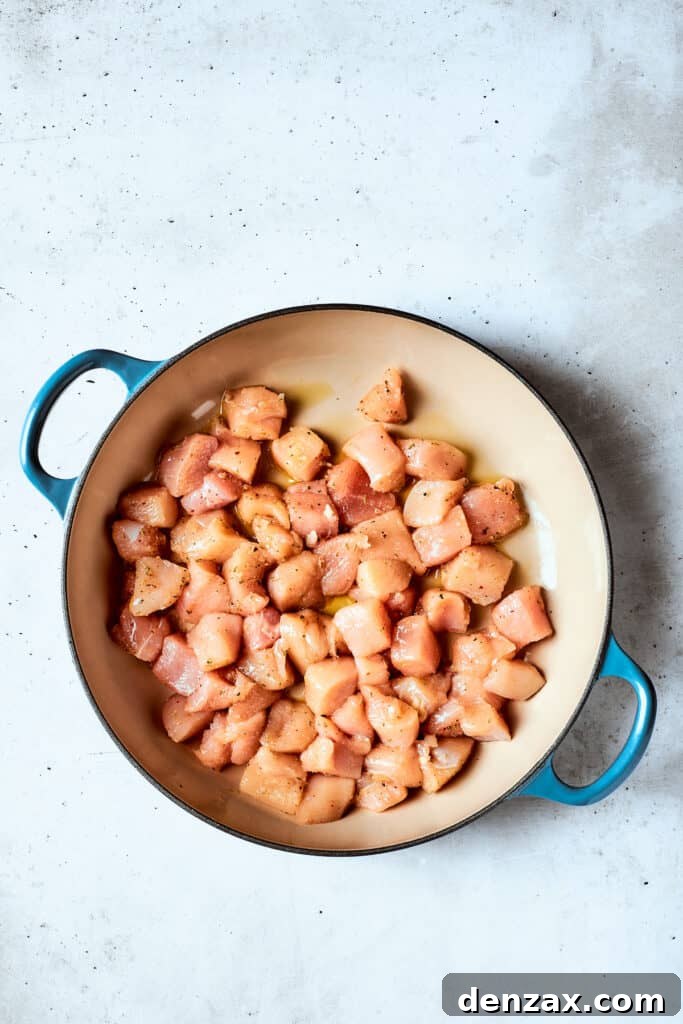 Cubed chicken pieces cooking in a pot.