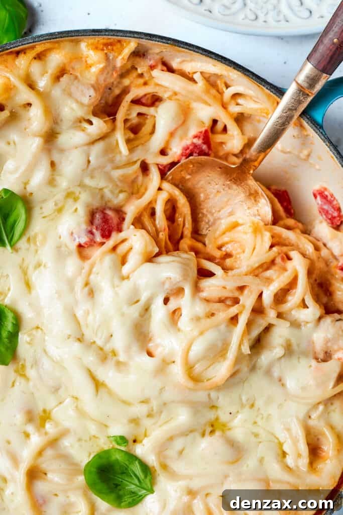 A spoon scooping into a pot of cheesy chicken spaghetti.