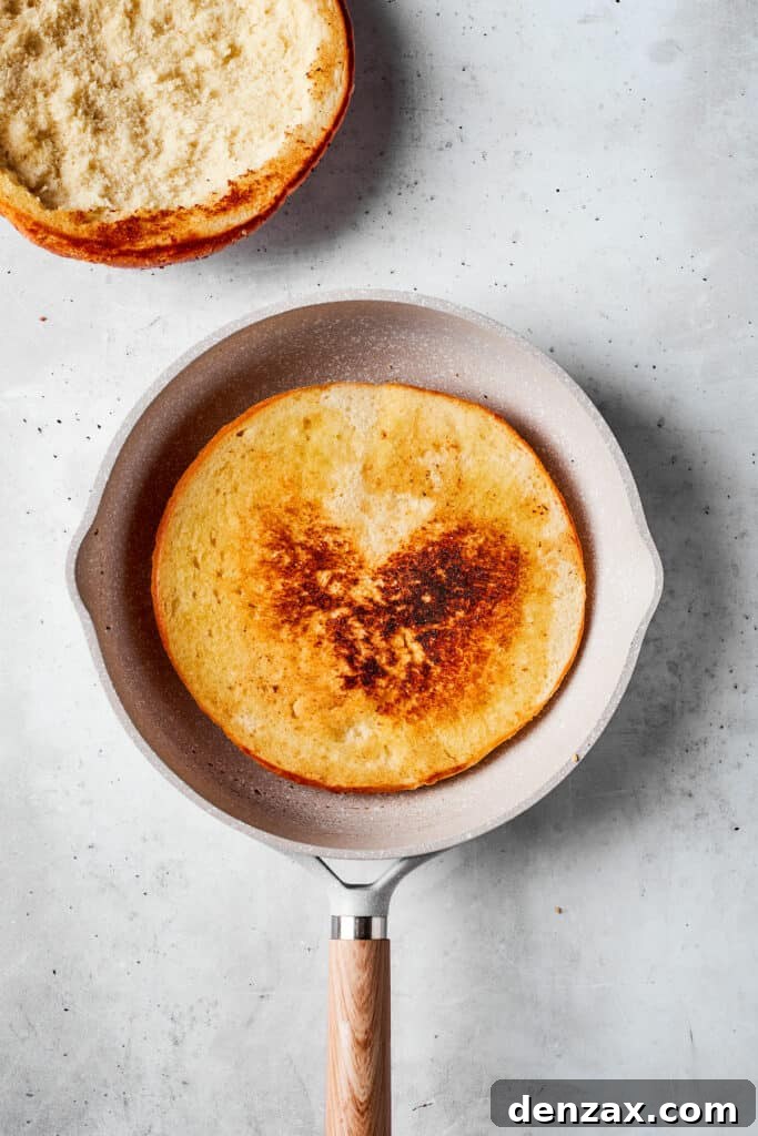 A half of muffaletta bread is toasted in a skillet.