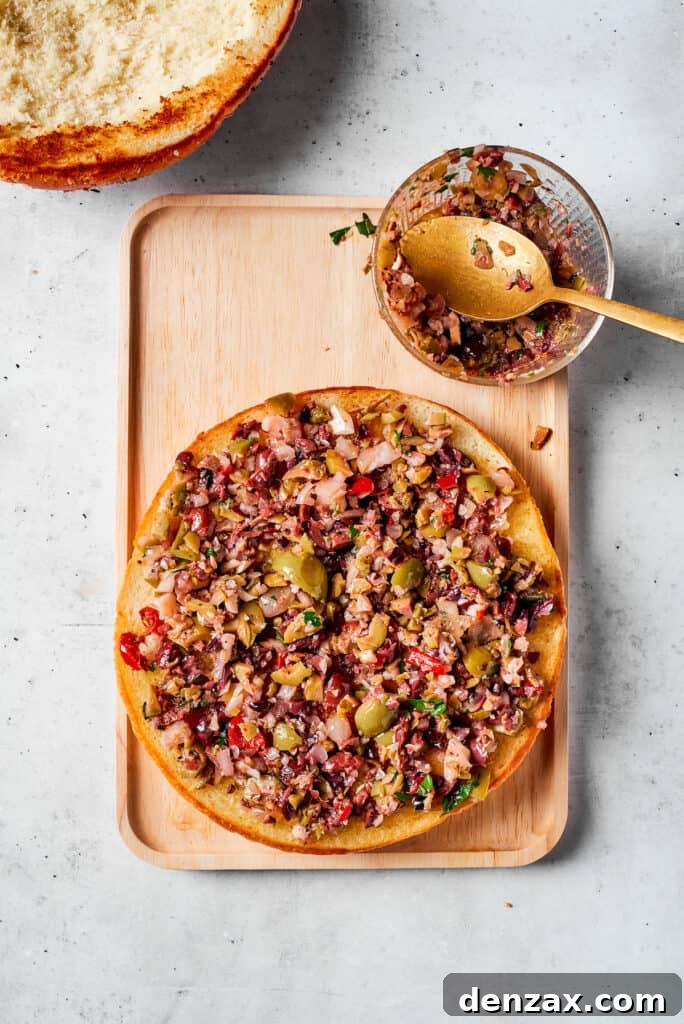 Olive salad is added to the other half of the bread.