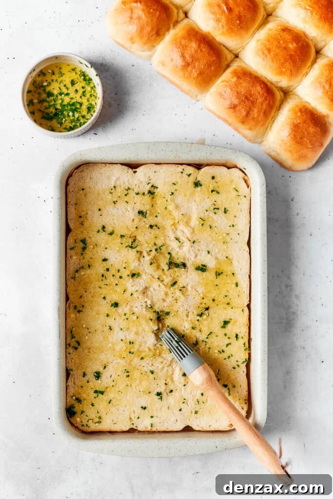 Chicken Bacon Ranch Sliders feature tender bites of shredded chicken, crisp bacon Ranch dressing, melted cheese, and sweet rolls. A melted butter mixture is added to a baking dish.