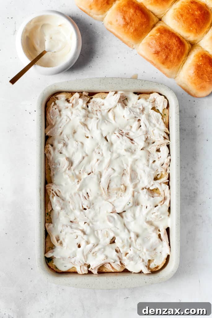Chicken Bacon Ranch Sliders feature tender bites of shredded chicken, crisp bacon Ranch dressing, melted cheese, and sweet rolls. Cheese and ranch top the chicken.