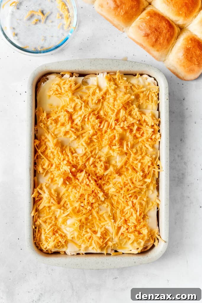 Chicken Bacon Ranch Sliders feature tender bites of shredded chicken, crisp bacon Ranch dressing, melted cheese, and sweet rolls. Shredded cheddar cheese spread on sliders.