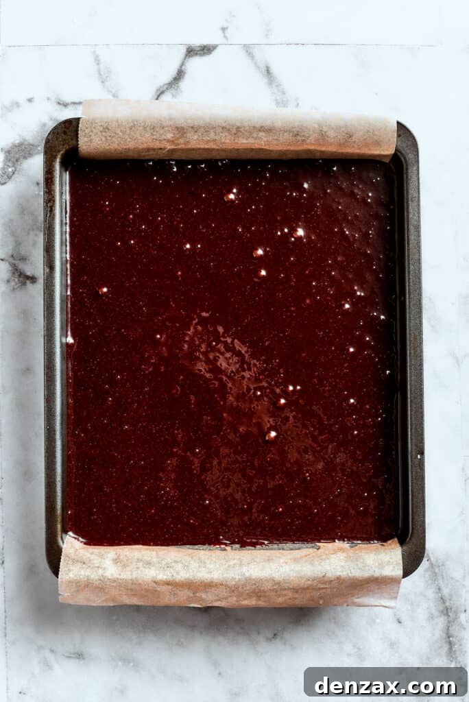 Brownie batter is spread into a baking pan.