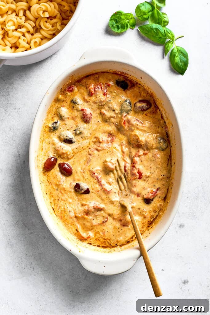 The melted cheese sauce with olives and tomatoes is shown in the baking dish.