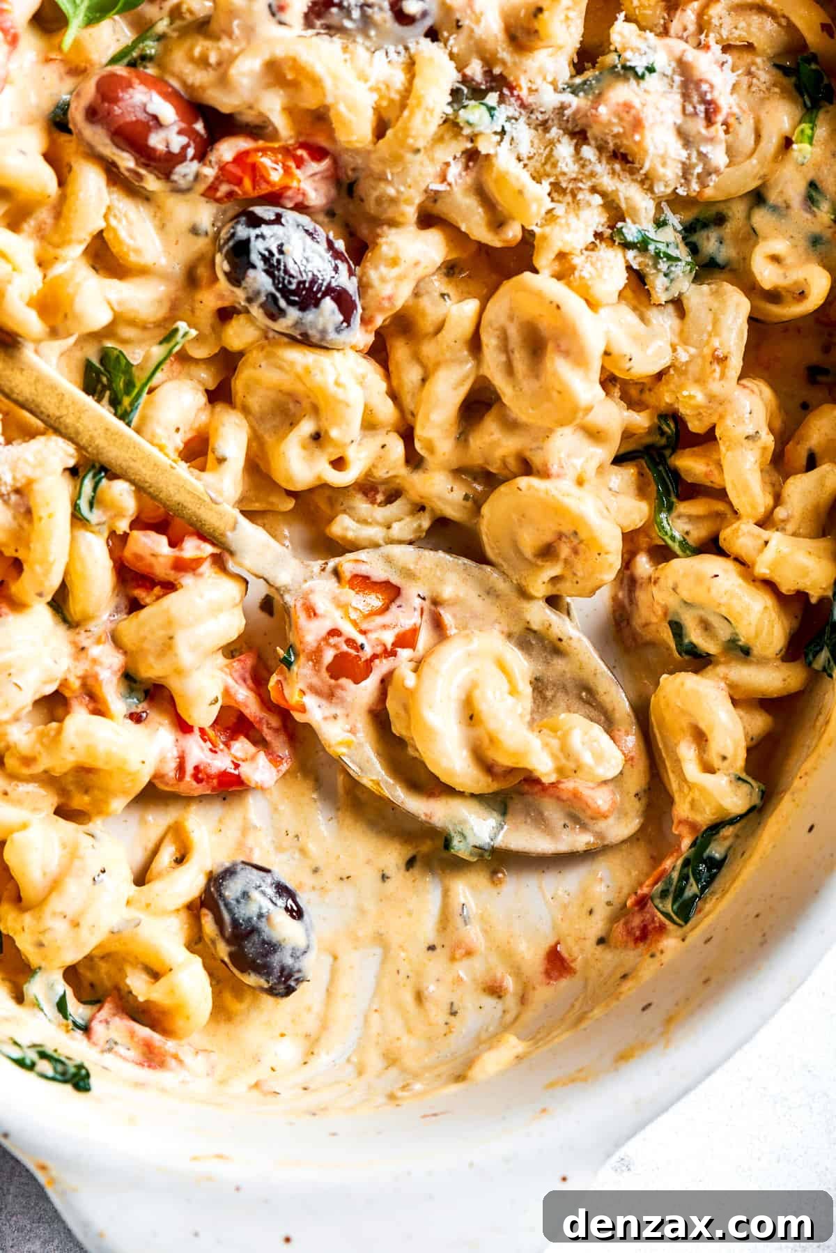Spooning out Boursin pasta from a baking dish.