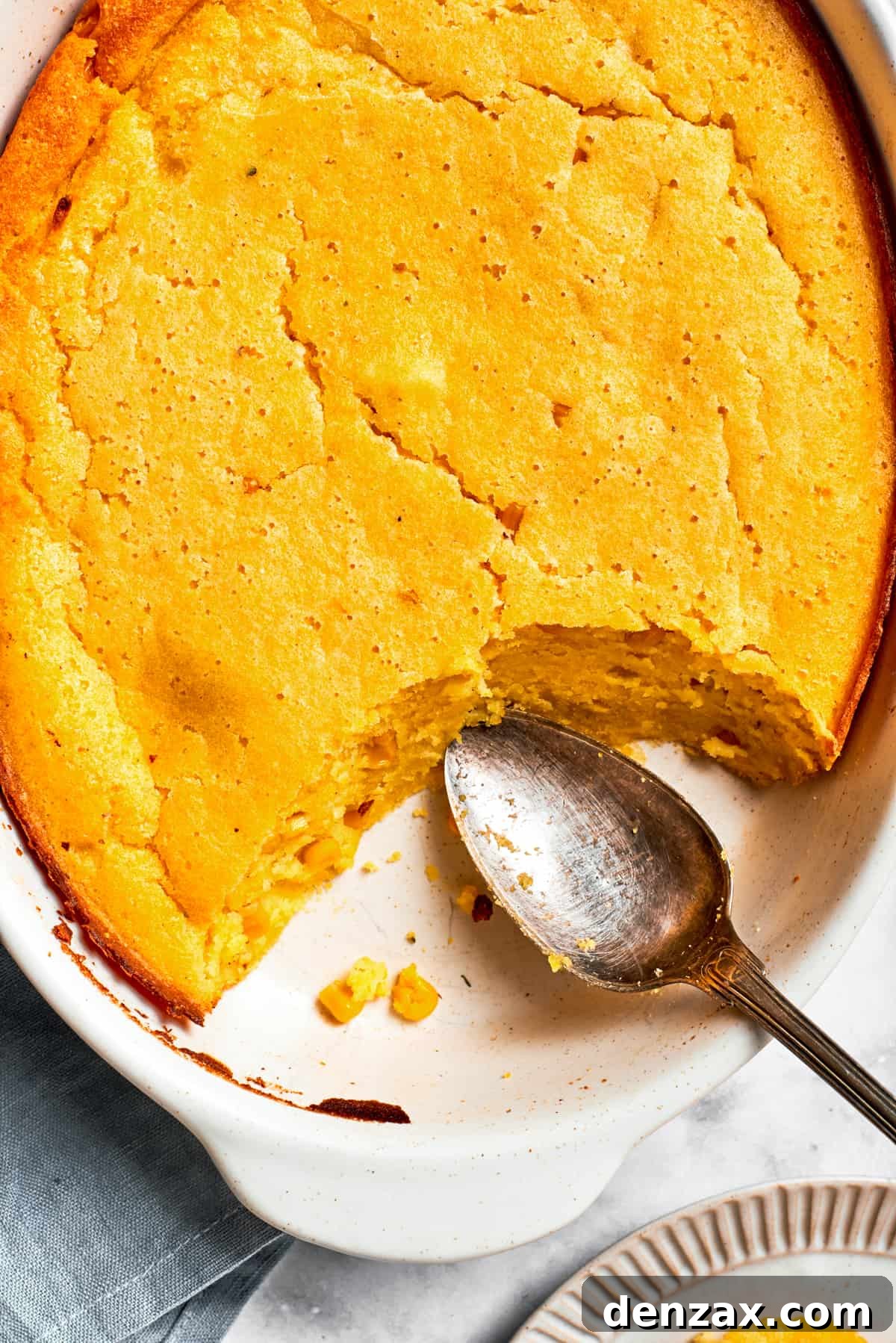 Serving spoon resting next to a baked bread in a casserole dish.