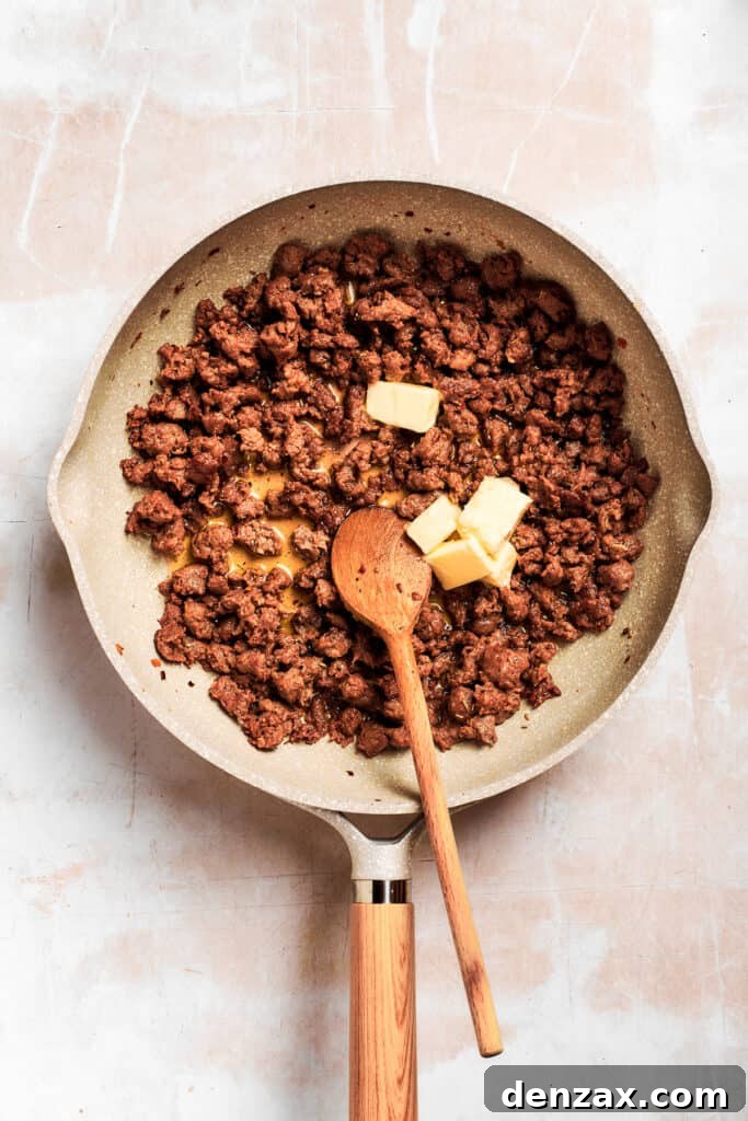 Butter is added to the sausage in the pan.