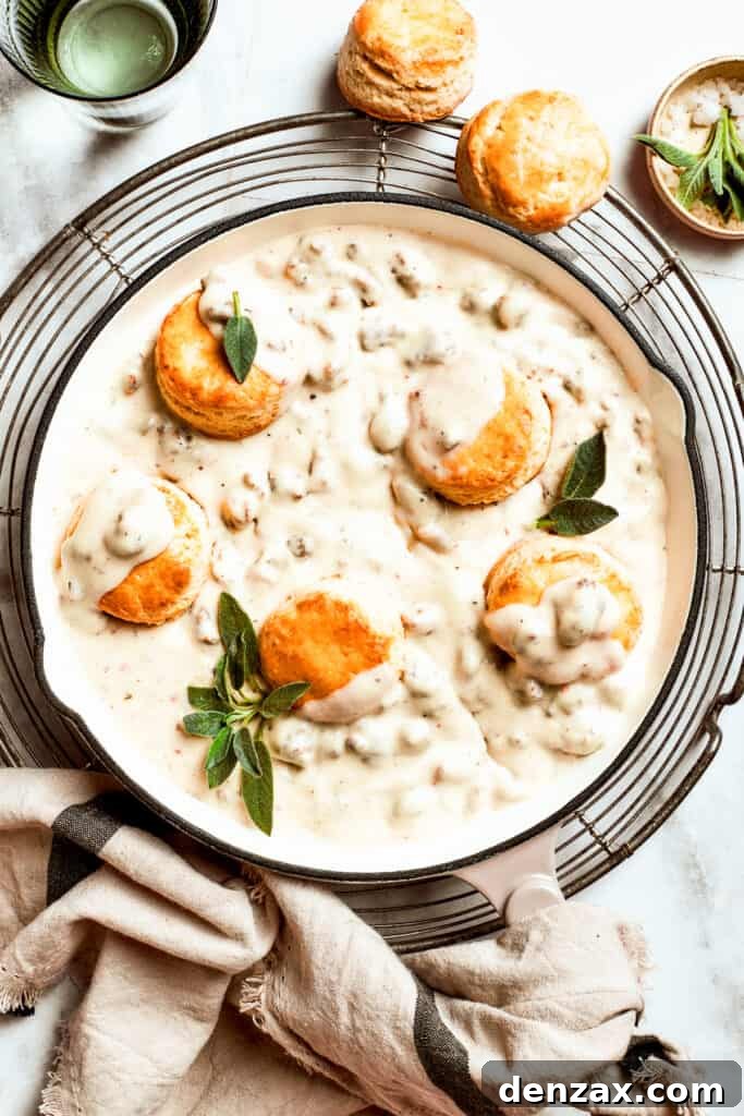 Five biscuits rest in a pan of sausage and gravy.