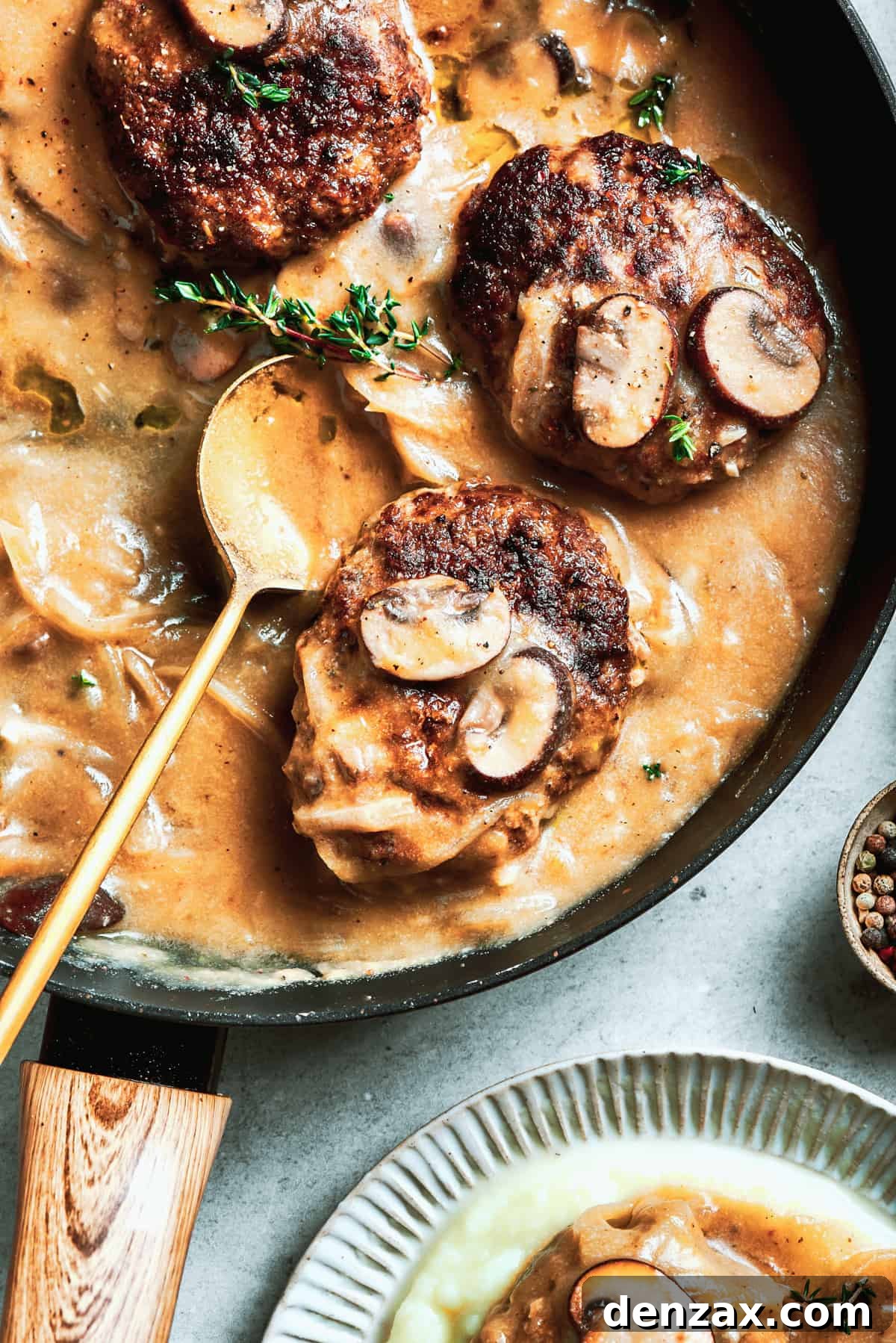 A pan of steak and gravy with a serving spoon resting in it.