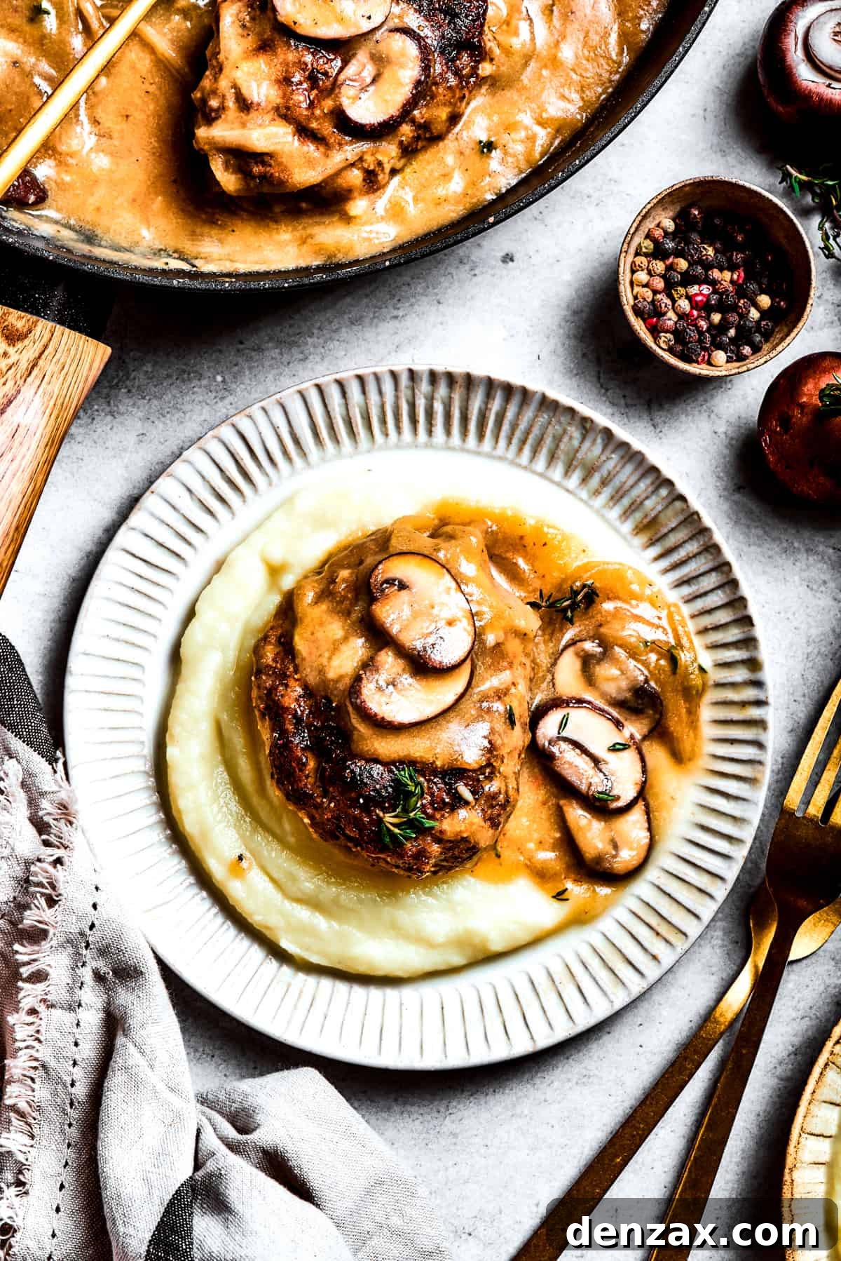 A serving of chopped steak on top of mashed potatoes.