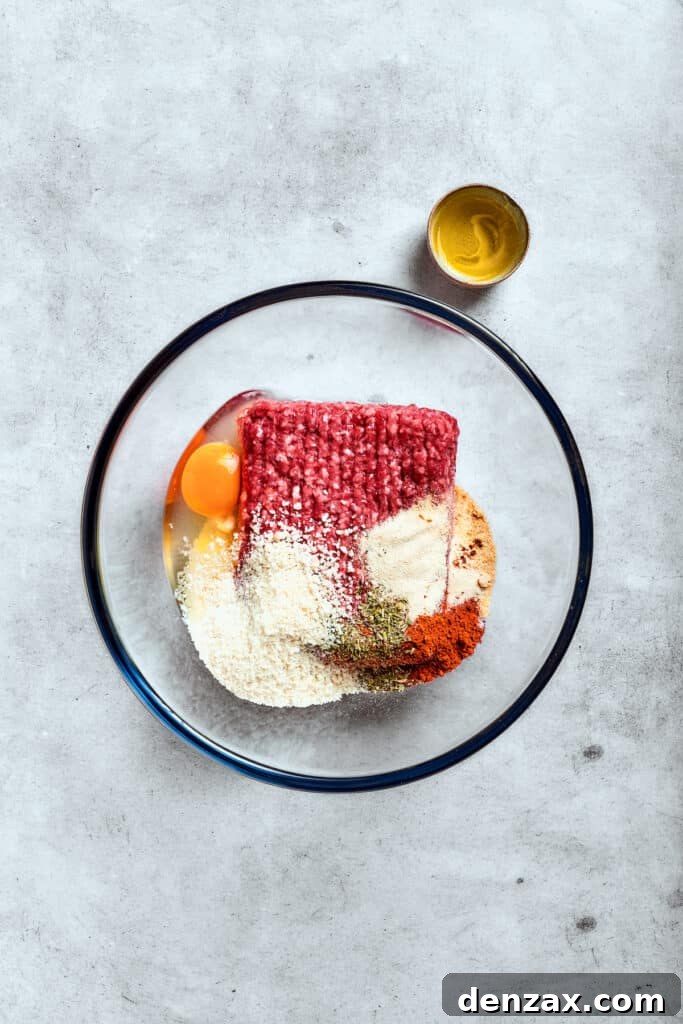 Ground beef, an egg, and breadcrumbs in a glass bowl.