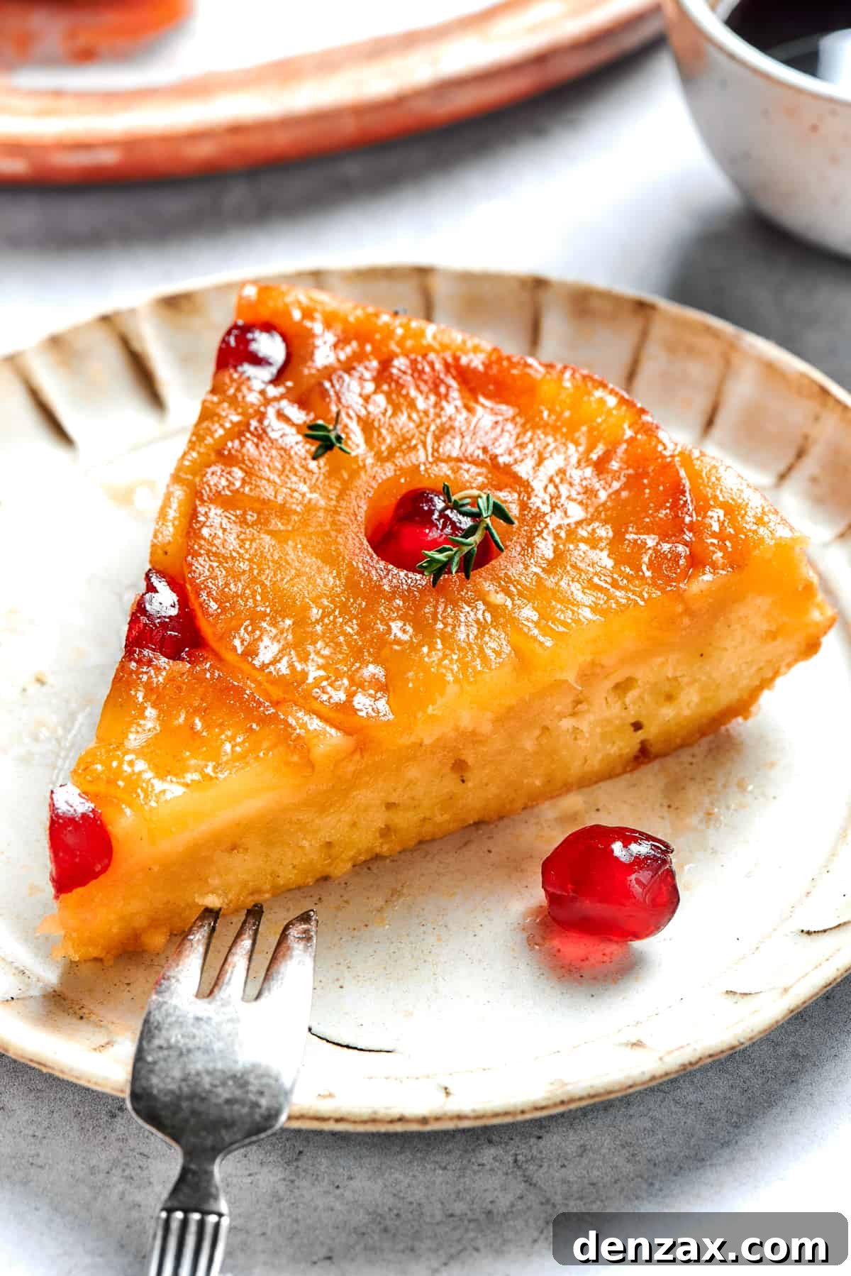 Slice of pineapple upside-down cake. Slice of pineapple upside down cake served on a plate with a fork next to it.