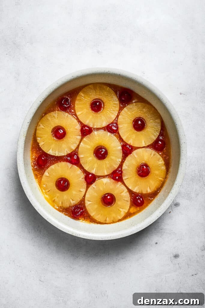 Arrange pineapple rings and cherries over the butter mixture. Cherries are added to the pineapple rings.