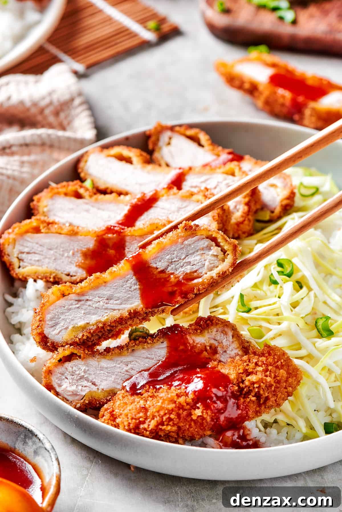 Chopsticks picking up a piece of pork katsu.