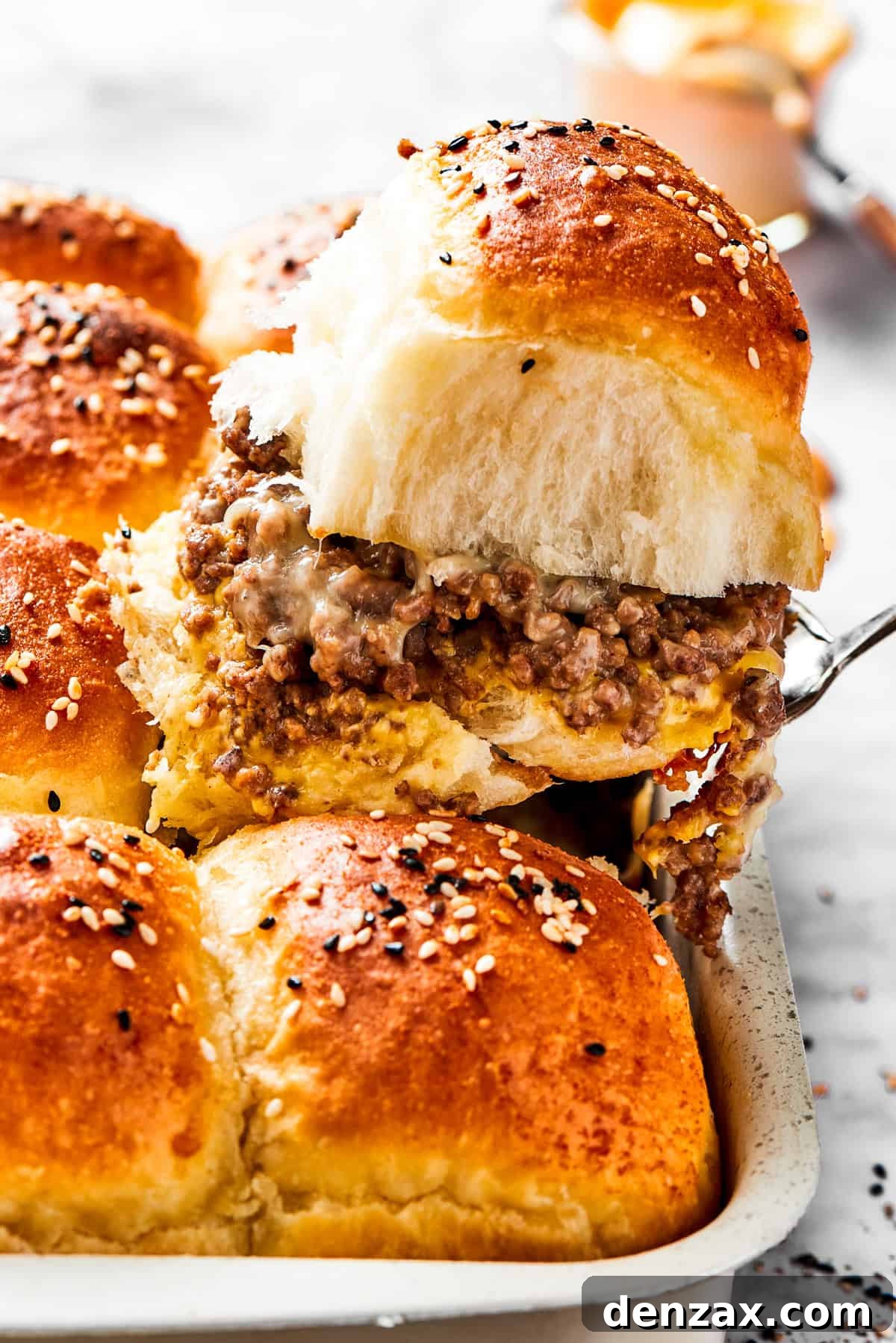 Cheeseburger slider on a spatula. A spatula holding up a sandwich with burger buns filled with ground meat.
