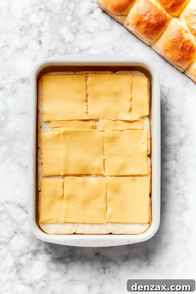 Layer cheese on rolls. Slices of cheese are placed on top of rolls.