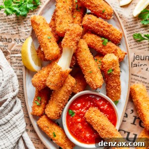 A platter of mozzarella sticks with one cut in half and one dipped in tomato sauce.