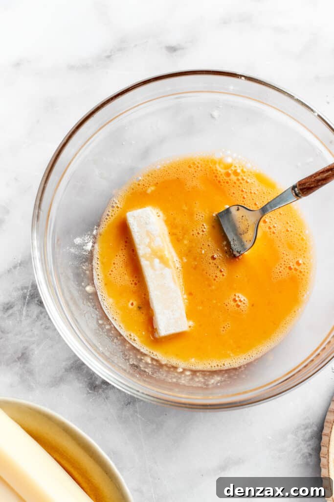 A piece of mozzarella is placed in beaten egg.