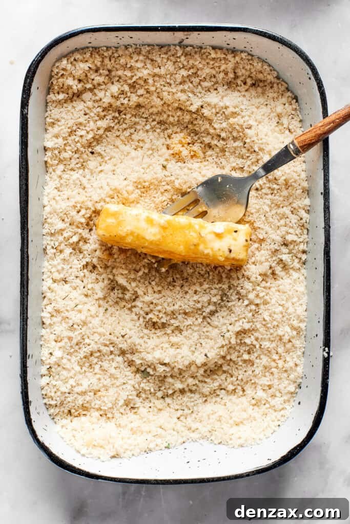 A tray of breadcrumbs with a piece of mozzarella in it.