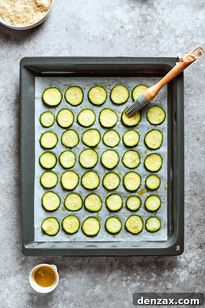 A pastry brush brushes the zucchini chips with oil.
