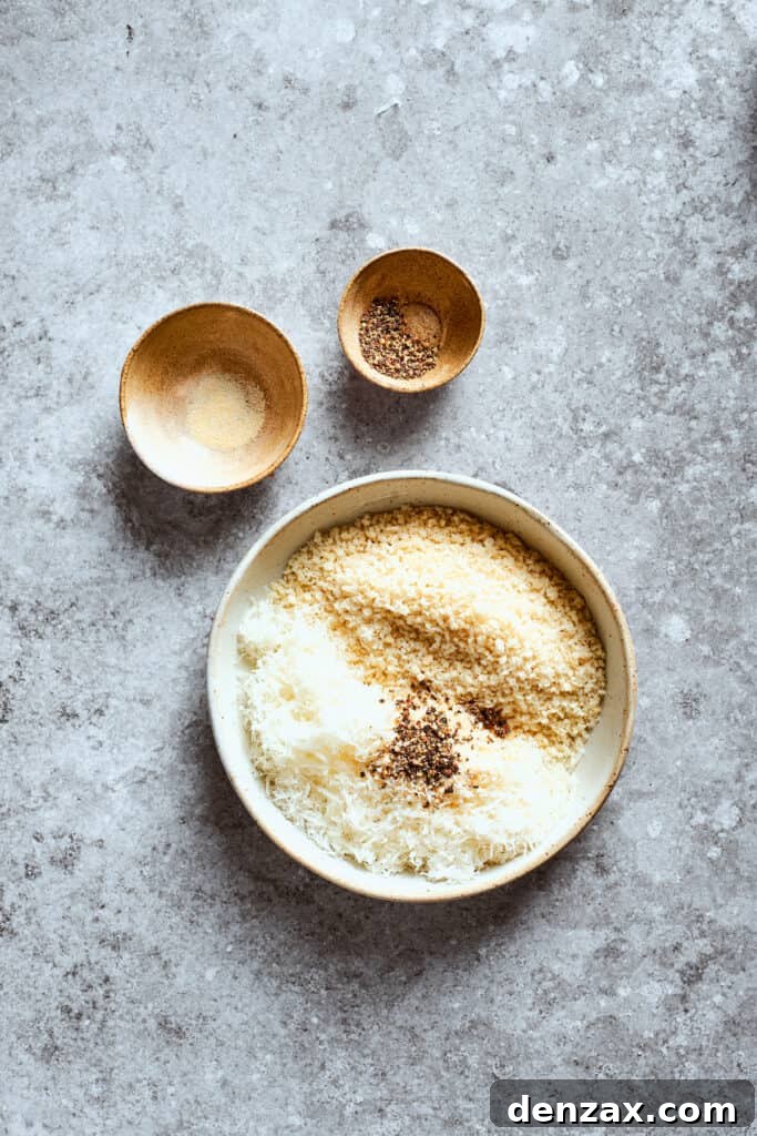 A bowl of breadcrumbs and parmesan next to bowls of seasoning.