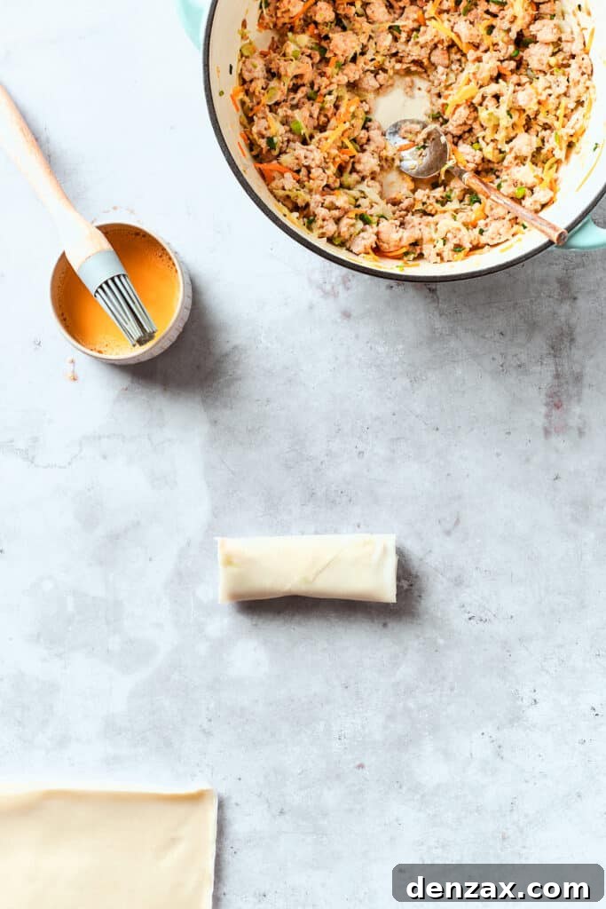 Egg wash is brushed on a chicken egg roll.